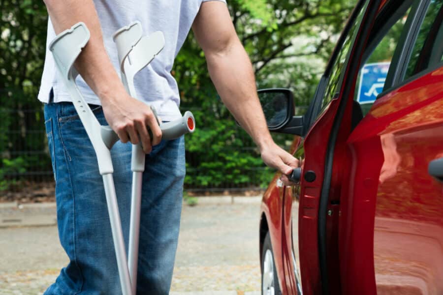 Homme en situation d'handicap physique qui ouvre la portière d'une voiture