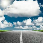 Photo d'une route en premier plan avec un ciel parsemé de nuages dans un second plan