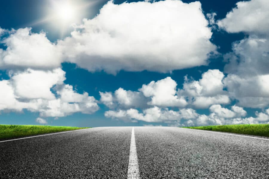Photo d'une route en premier plan avec un ciel parsemé de nuages dans un second plan