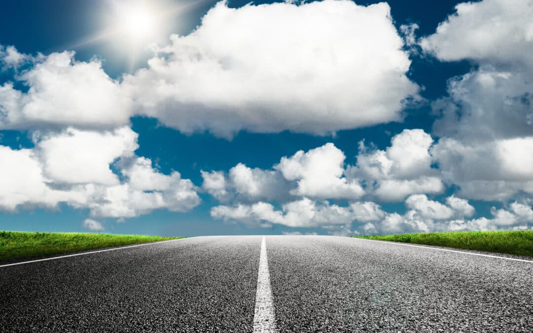 Photo d'une route en premier plan avec un ciel parsemé de nuages dans un second plan