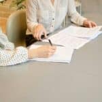 Personne qui signe un papier et une personne aidant cette dernière