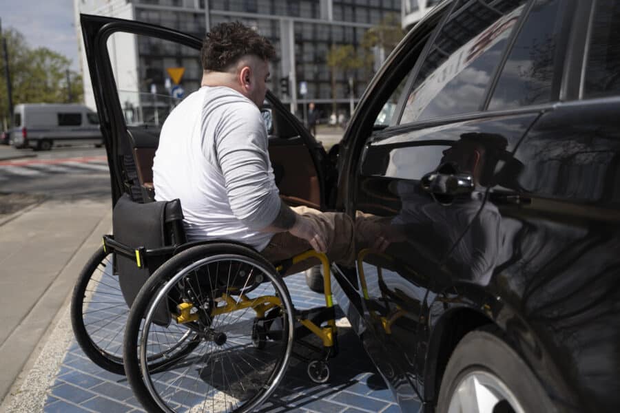 personne en fauteuil roulant montant dans son véhicule